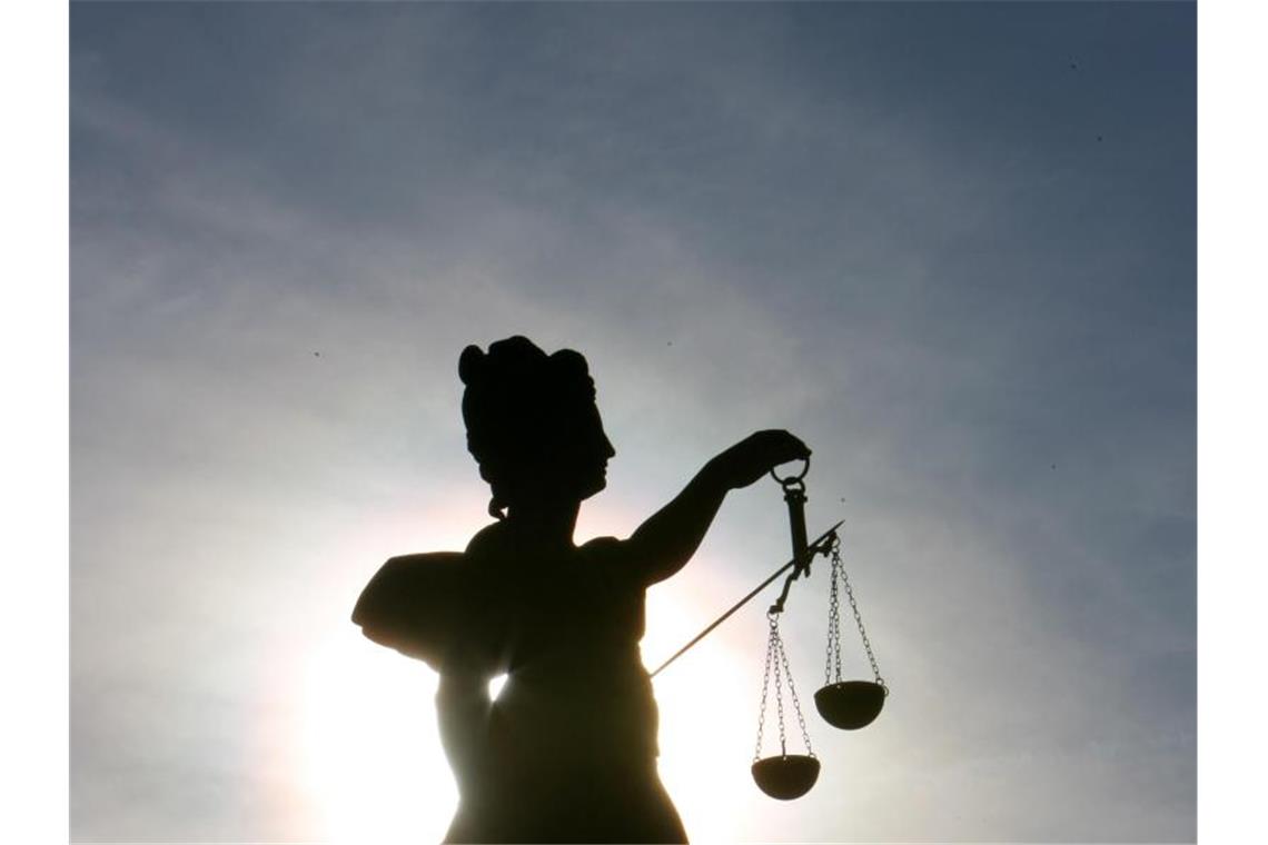 Verband kontra Waschmittelwerbung: OLG-Prozess beginnt Die Göttin Justitia thront im Gegenlicht auf einem Brunnen. Foto: Arne Dedert/dpa