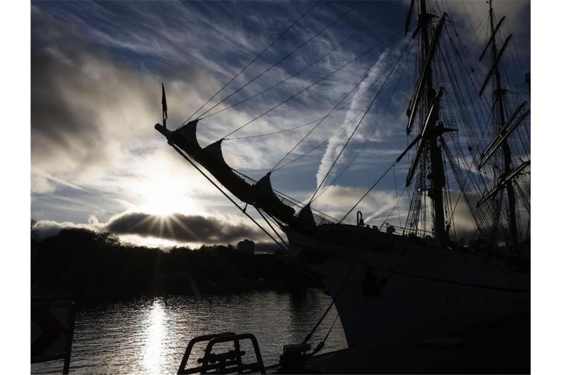 Die „Gorch Fock“ liegt im Gegenlicht an ihrem Liegeplatz in Kiel. (Archivbild). Foto: Frank Molter/dpa