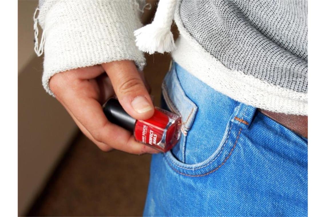 Die Hand einer jungen Frau steckt ein Fläschchen Nagellack in die Tasche. Foto: Katharina Heimeier/dpa