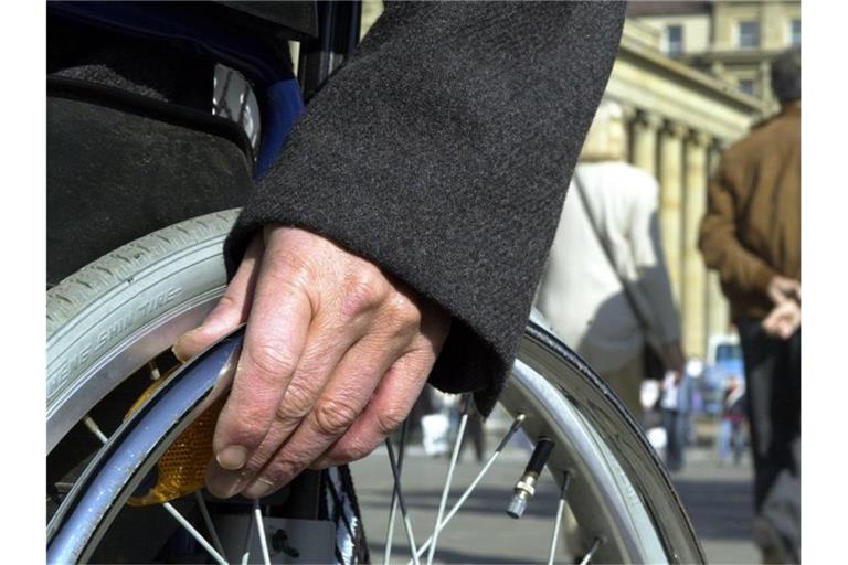 Die Hand eines Rollstuhlfahrers liegt auf dem Stuttgarter Schlossplatz auf dem Rad. Foto: Norbert Försterling/Archiv