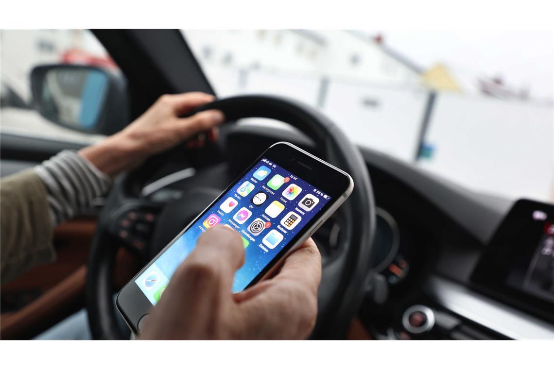 Die Handynutzung am Steuer ohne Freisprechanlage oder Halterung kann hohe Strafen mit sich bringen.