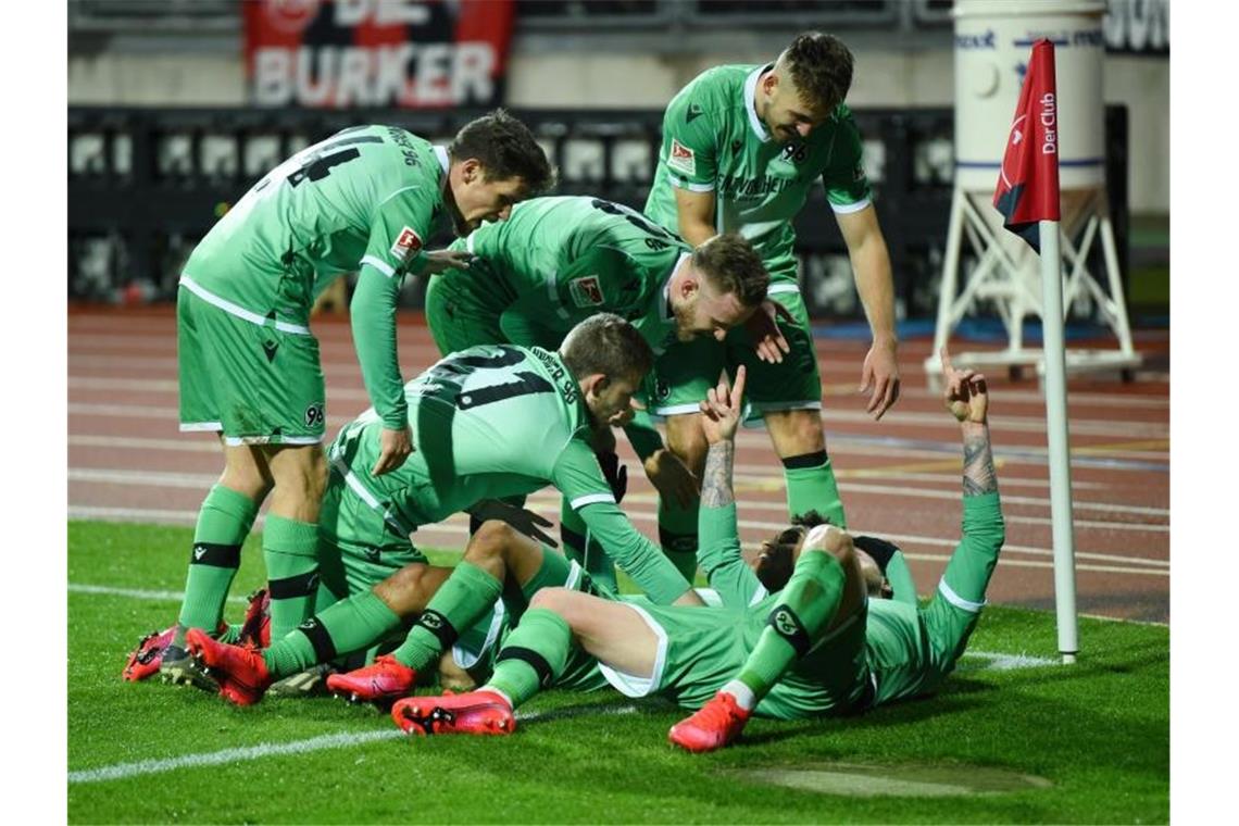 Die Hannover Spieler feiern den 2:0-Treffer von Linton Maina (verdeckt). Foto: Nicolas Armer/dpa