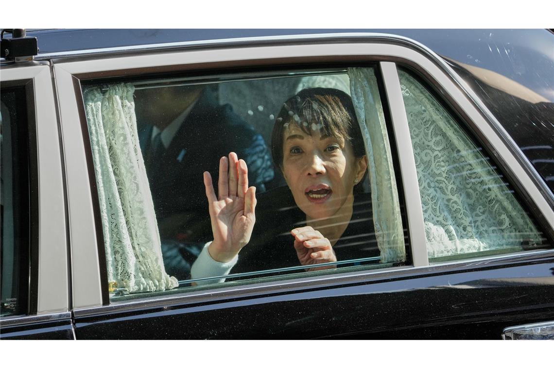 Die japanische Premierministerin Sanae Takaichi winkt von ihrem Fahrzeug aus.
