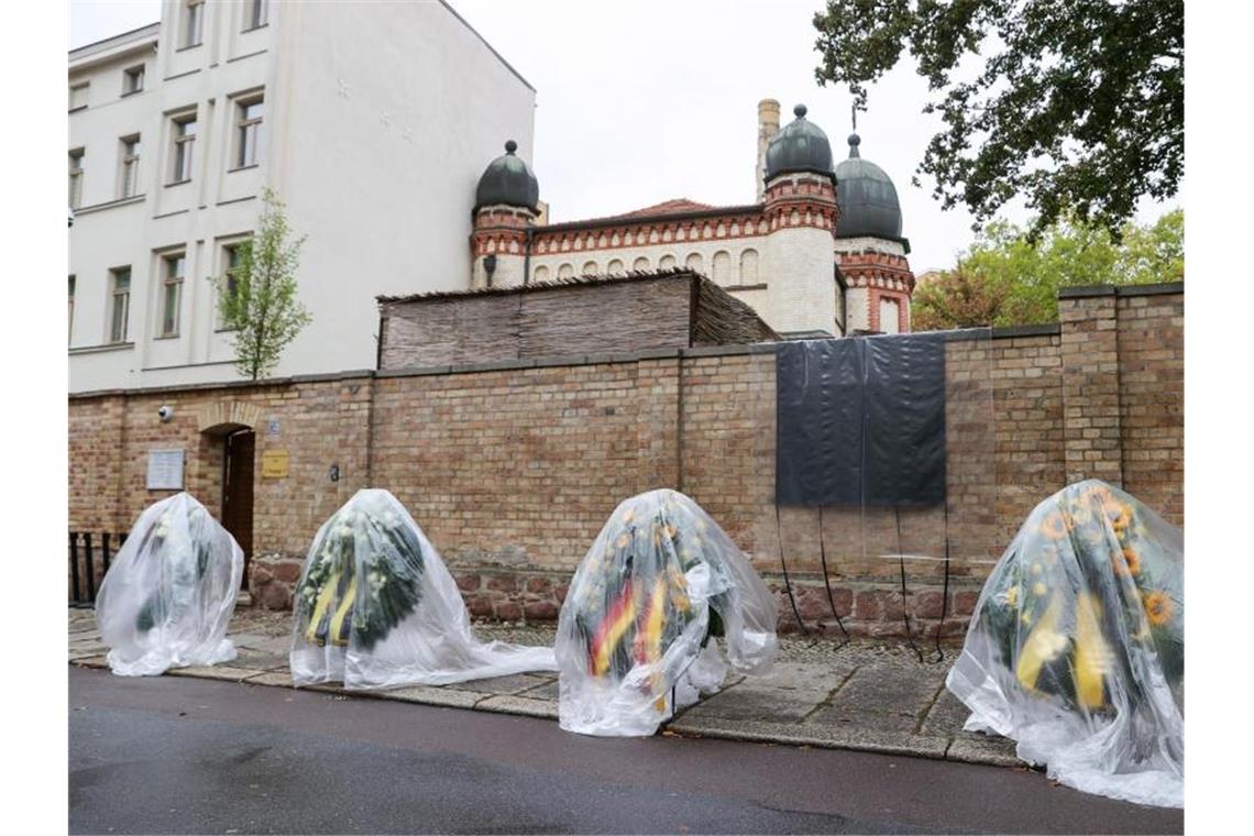Halle gedenkt der Terror-Opfer Die Kränze für den Gedenktag an den Anschlag in Halle stehen mit Regenfolie überzogen vor der Synagoge. Foto: Jan Woitas/dpa-Zentralbild/dpa