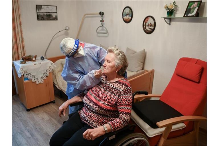 Die Krankenschwester eines mobilen Test-Teams des Deutschen Roten Kreuzes (DRK) testet in einer DRK-Seniorenbetreuungseinrichtung in Brandenburg eine Seniorin. Foto: Jens Kalaene/dpa-Zentralbidl/dpa