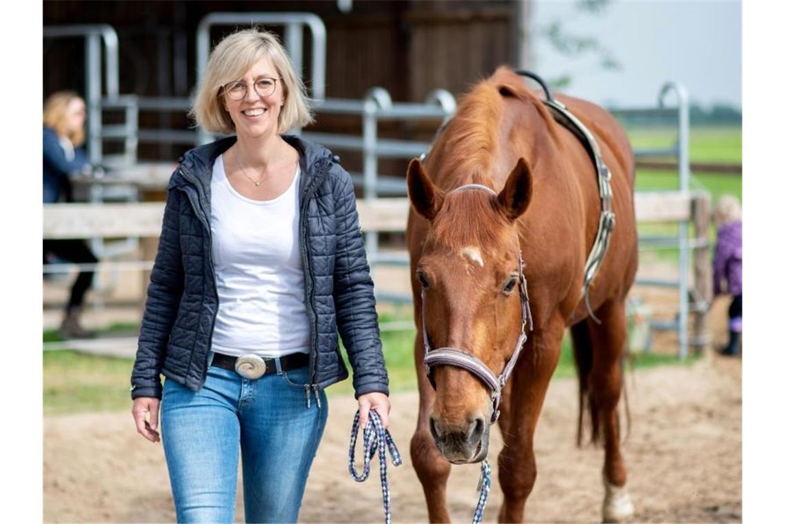 Die Landwirtin Martina Warnken geht mit Pferd „Wilma“ über einen Reitplatz. Foto: Hauke-Christian Dittrich/dpa/Archivbild