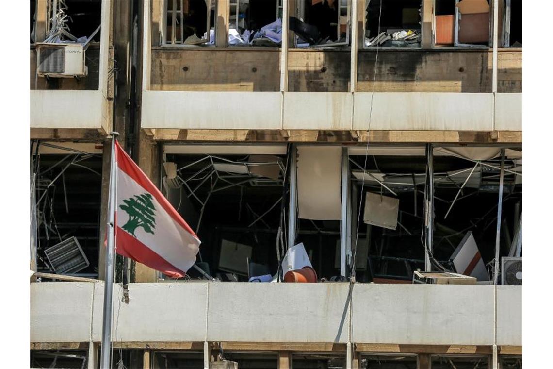 Die libanesische Flagge vor der Fassade eines zerstörten Bürogebäudes in Beirut. Foto: Marwan Naamani/dpa
