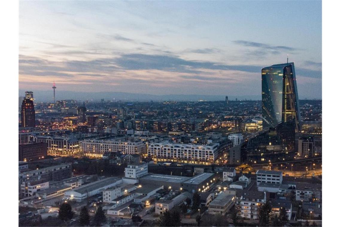 Die Lichter in den Büros der Europäischen Zentralbank (r) leuchten im Abendlicht. Foto: Boris Roessler/dpa