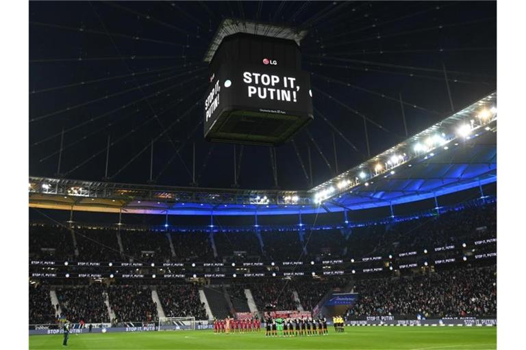 Die Mannschaften von Eintracht Frankfurt und dem FC Bayern München stehen vor dem Spiel während einer Schweigeminute für die Ukraine zusammen. Foto: Arne Dedert/dpa