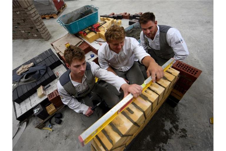 Die Maurer (l-r) Pierre Holze, Christoph Rapp und Jannes Wulfes kontrollieren eine Mauer. Foto: Stefan Puchner/Archivbild