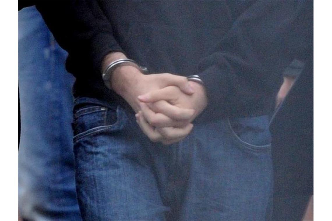 Die mit Handschellen gefesselten Hände eines mutmaßlichen Terroristen. (Symbolbild). Foto: Franziska Kraufmann/dpa
