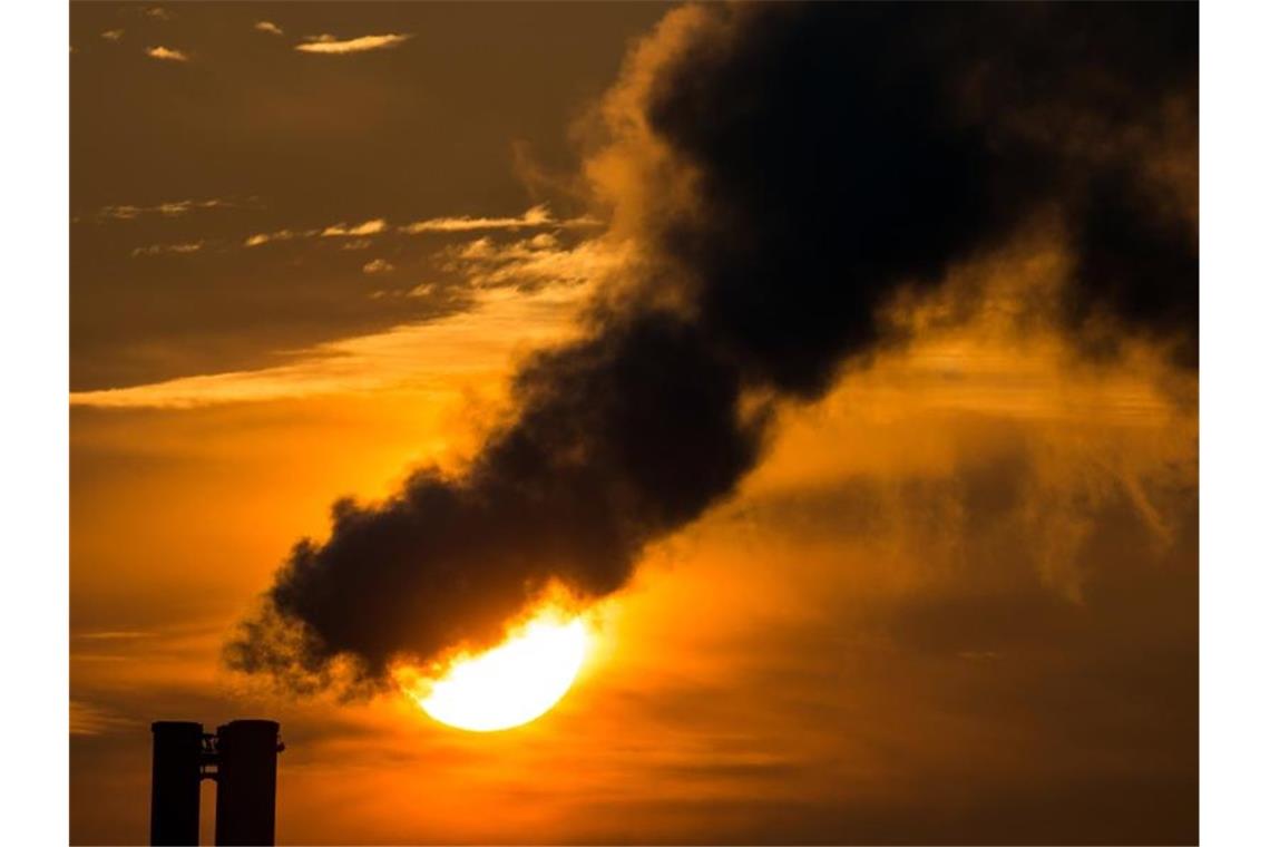 Die Morgensonne hinter qualmenden Schornsteinen eines Blockheizkraftwerkes. Foto: Patrick Pleul/dpa