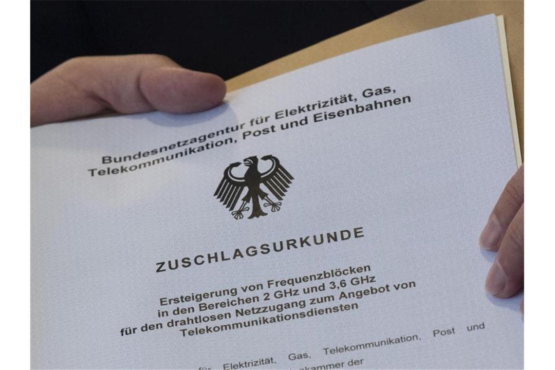 Vorbereitungen für 5G-Netze laufen an Die offizielle „Zuschlagsurkunde“ wird dem Vertreter eines Mobilfunkunternehmens in den Räumen der Bundesnetzagentur übergeben. Foto: Boris Roessler