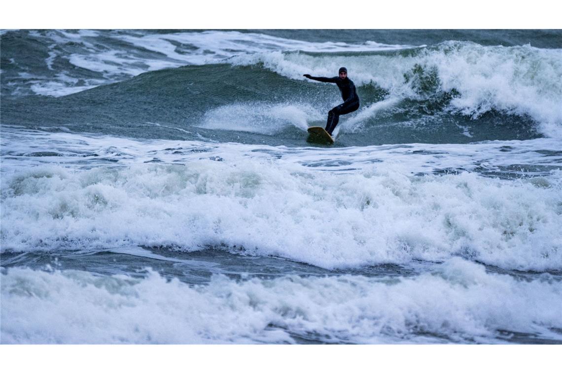 Die Ostsee zeigt sich an der Küste der Insel Rügen heute stürmisch - ein Surfer lässt sich von den Wellen und der Kälte trotzdem nicht beirren.
