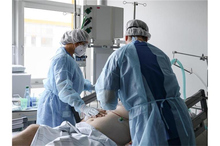Die pflegerische Leitung der Intensivstation und Intensivstationsarzt bei einem Corona-Patienten auf der Intensivstation. (Archivbild). Foto: Daniel Vogl/dpa