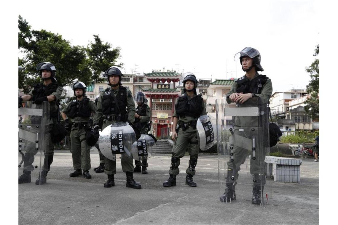 Die Polizei bezieht in schwerer Schutzausrüstung Stellung am Rande der Demonstration. Foto: Bobby Yip/AP