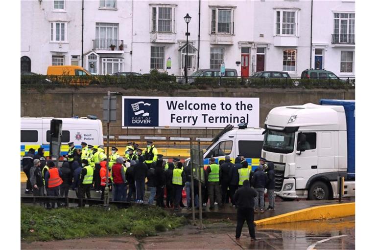 Die Polizei hält Fahrer zurück, die versuchen, in den Hafen von Dover zu laufen. Am englischen Hafen Dover ist es zwischen wartenden Lkw-Fahrern und der Polizei zu Schubsereien und Handgemenge gekommen. Foto: Steve Parsons/PA Wire/dpa