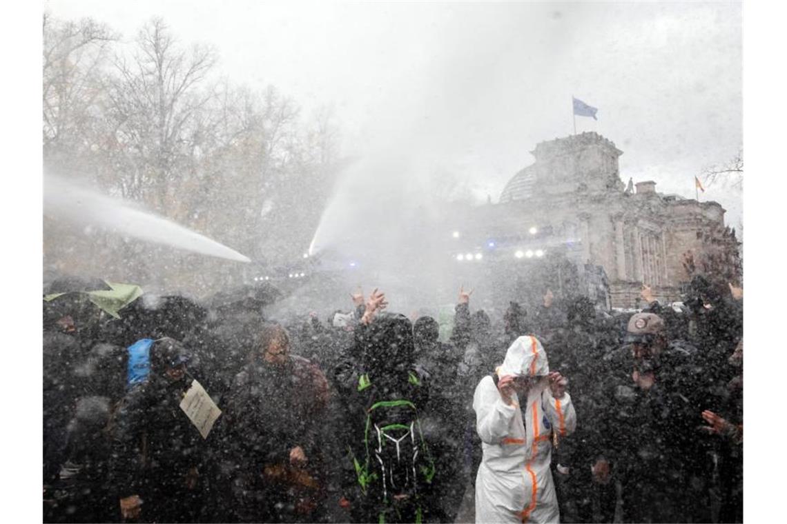 Die Polizei setzt bei einer Demonstration gegen die Corona-Einschränkungen der Bundesregierung am Brandenburger Tor unweit des Reichstagsgebäudes (hinten) Wasserwerfer ein. Foto: Christoph Soeder/dpa