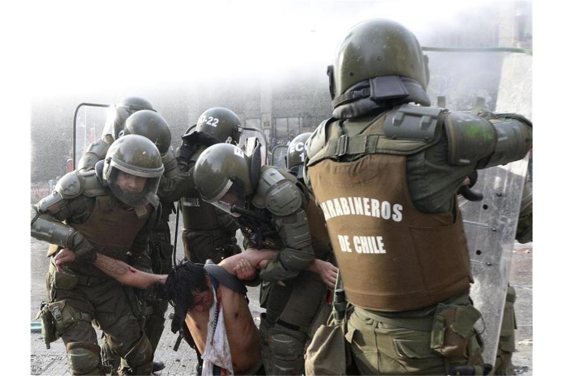 Nach blutigen Protesten: Chile soll neue Verfassung bekommen Die Polizei trägt einen regierungsfeindlichen Demonstranten, der bei Zusammenstößen verletzt wurde. Foto: Esteban Felix/AP/dpa
