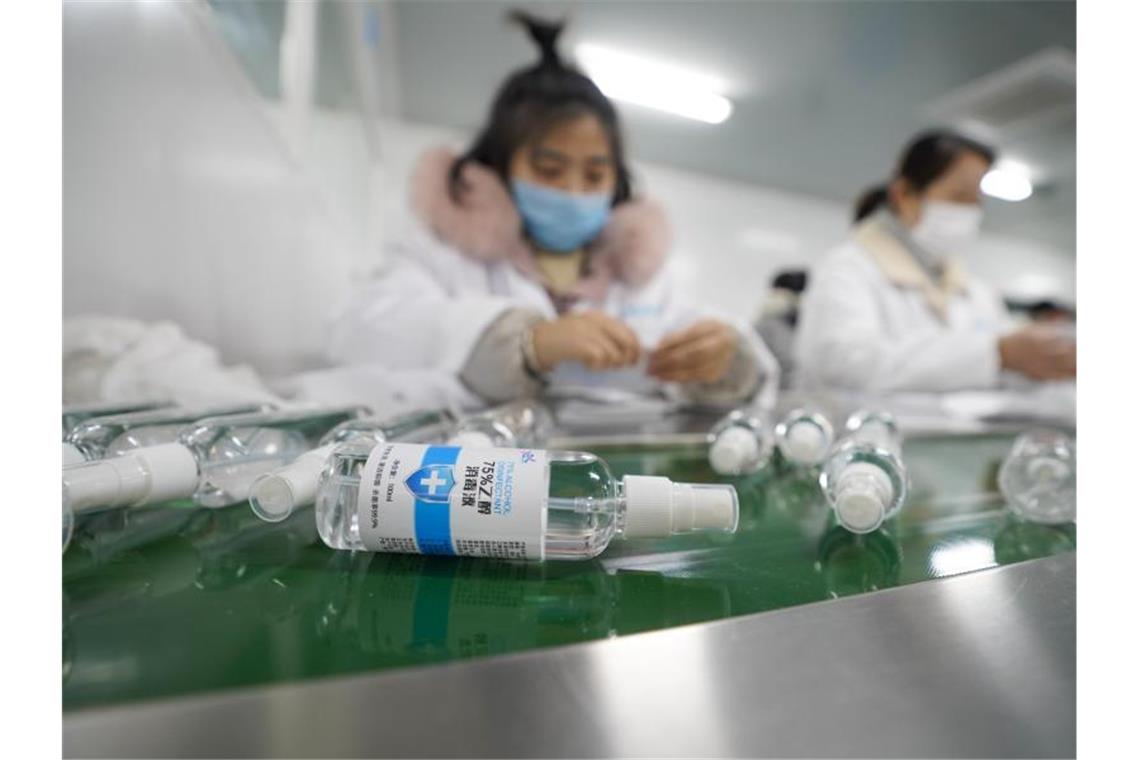 Die Produktion von Desinfektionsmittel wird in China massiv ausgeweitet. In einem Betrieb in Chongqing bringt eine Mitarbeiterin an einem Fließband Etiketten auf Flaschen an. Foto: Liu Chan/Xinhua/dpa