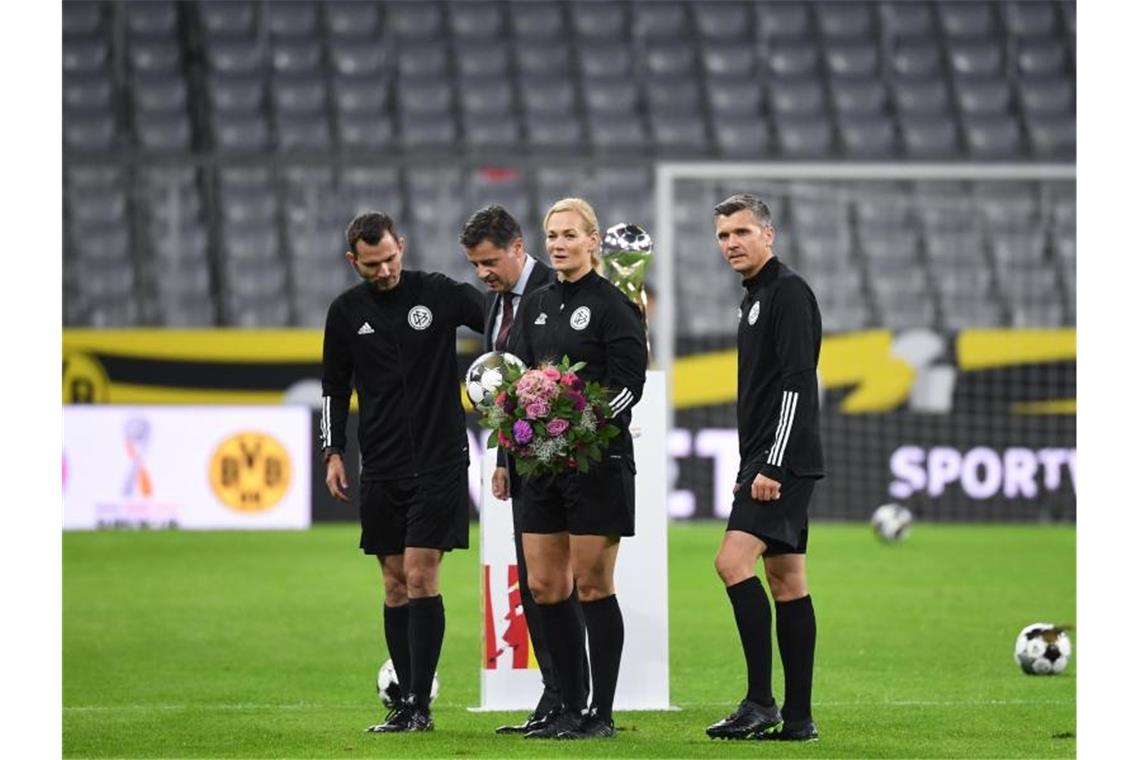 Die scheidende Schiedsrichterin Bibiana Steinhaus wurde vor dem Anpfiff von DFL-Boss Christian Seifert (2.v.l) mit Blumen bedacht. Foto: Sven Hoppe/dpa-Pool/dpa