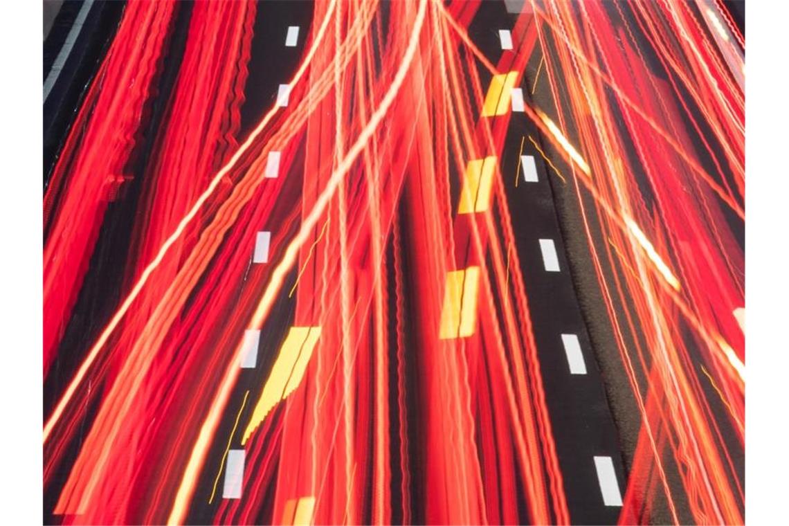 Die Scheinwerfer vorbeifahrender Fahrzeuge ziehen auf einer Autobahn ihre Lichtspuren durch die hereinbrechende Dunkelheit (Aufnahme mit Langzeitbelichtung). Foto: Boris Roessler/dpa