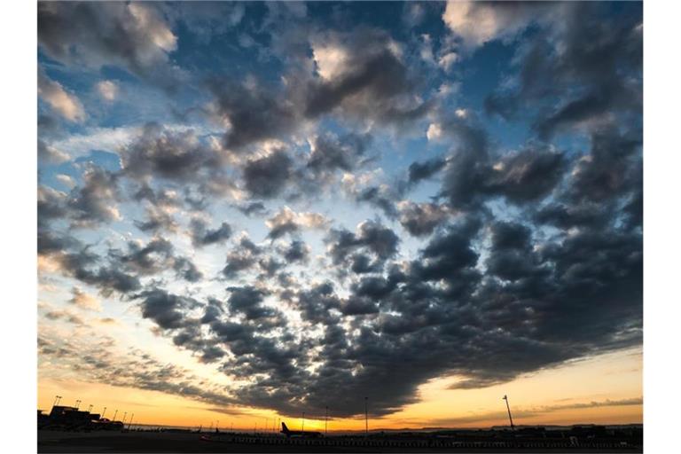 Die Sonne geht auf und färbt dabei vorbeiziehende Wolken. Foto: Christoph Schmidt/dpa/Archivbild