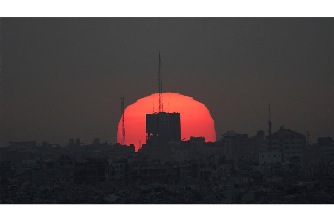 Die Sonne geht hinter beschädigten Gebäuden im Gazastreifen unter, vom Süden Israels aus gesehen.