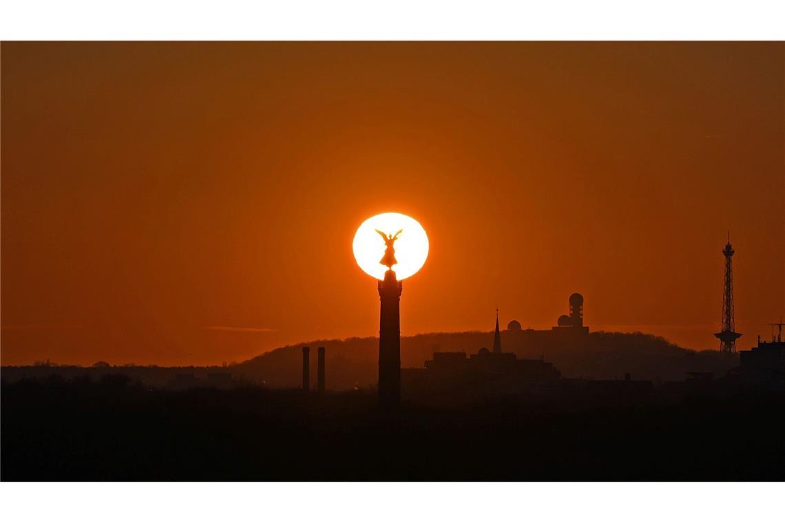 Die Sonne geht hinter der Siegessäule in Berlin unter.