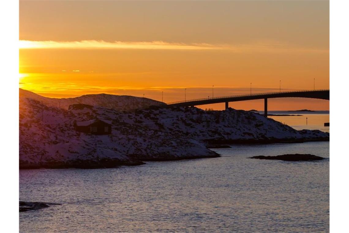 Die Sonne geht hinter der Sommaroy-Brücke unter, die die Inseln Kvaloya und Sommaroy verbindet. Foto: Hinrich Bäsemann