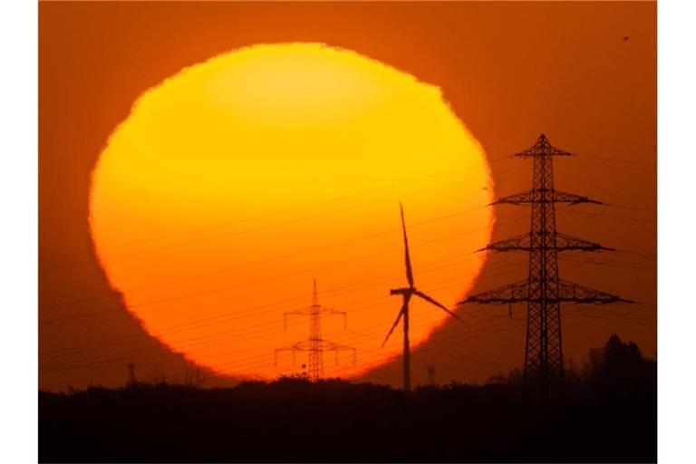 Die Sonne geht hinter Windrädern und Hochspannungsleitungen in der Region Hannover auf. Foto: Julian Stratenschulte/dpa