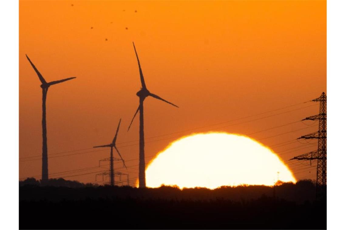 CDU: Mehr Ehrgeiz bei Windkraft und setzt Grüne unter Druck Die Sonne geht hinter Windrädern und Hochspannungsleitungen auf. Foto: Julian Stratenschulte/dpa/Symbolbild