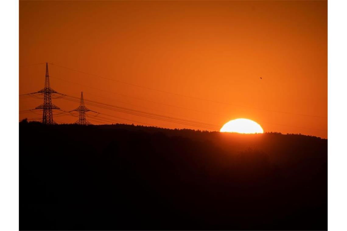 Die Sonne geht in Köngen neben zwei Strommasten auf. Foto: Marijan Murat/dpa
