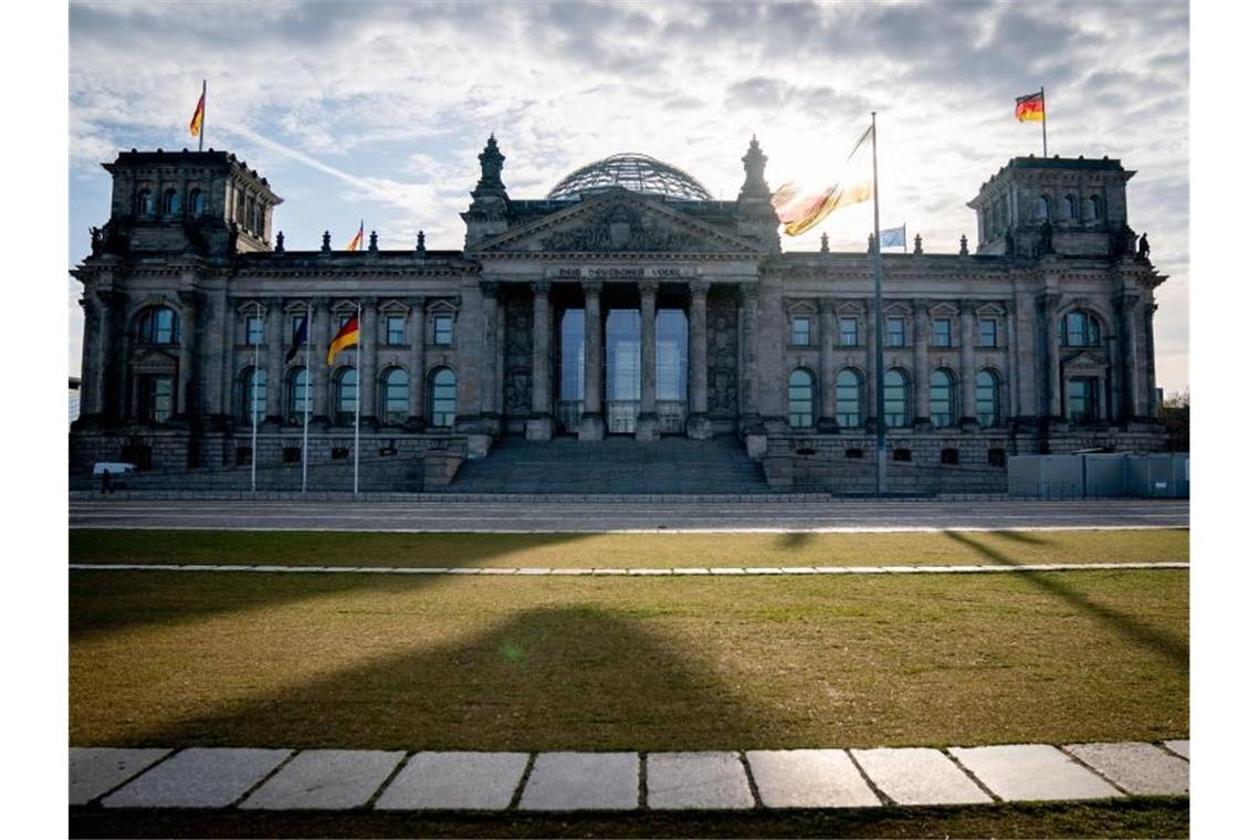 Die Sonne steht am Morgen hinter dem Reichstagsgebäude mit dem Bundestag. Foto: Kay Nietfeld/dpa