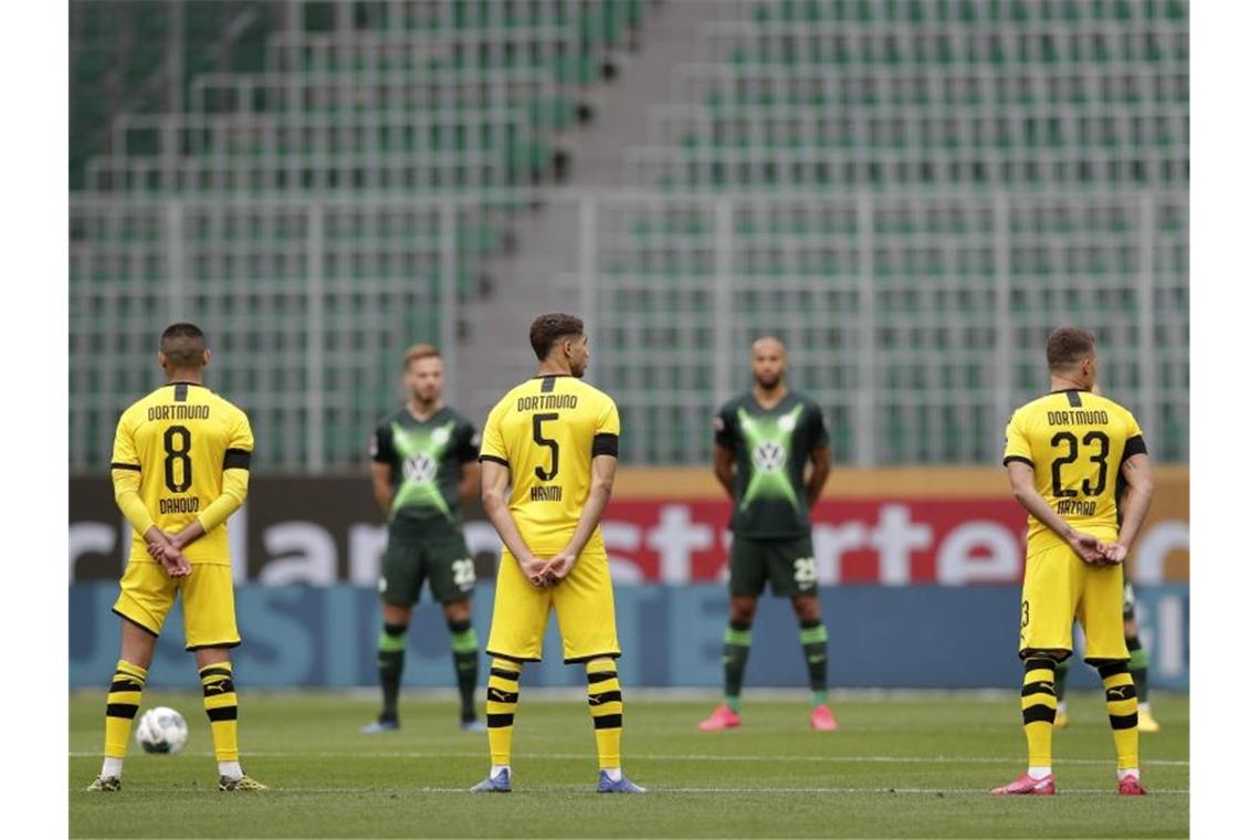 Die Spieler beider Mannschaften (Dortmund gelbes Trikot) gedenken mit einer Schweigeminute den Opfern der Corona-Pandemie. Foto: Michael Sohn/AP-Pool/dpa