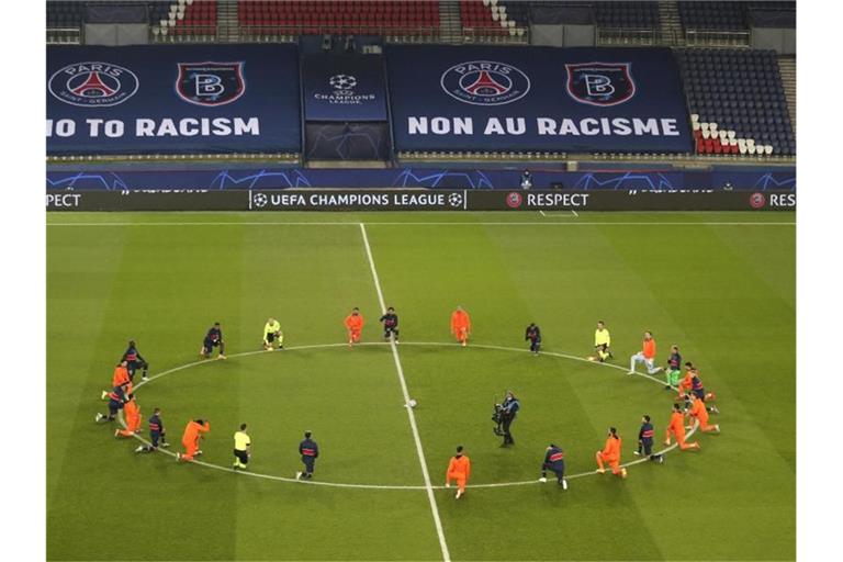 Die Spieler beider Teams und die Schiedsrichter beim Kniefall auf dem Platz als Zeichen der Unterstützung der Black Lives Matter-Bewegung. Foto: Xavier Laine/Getty/Pool/AP/dpa