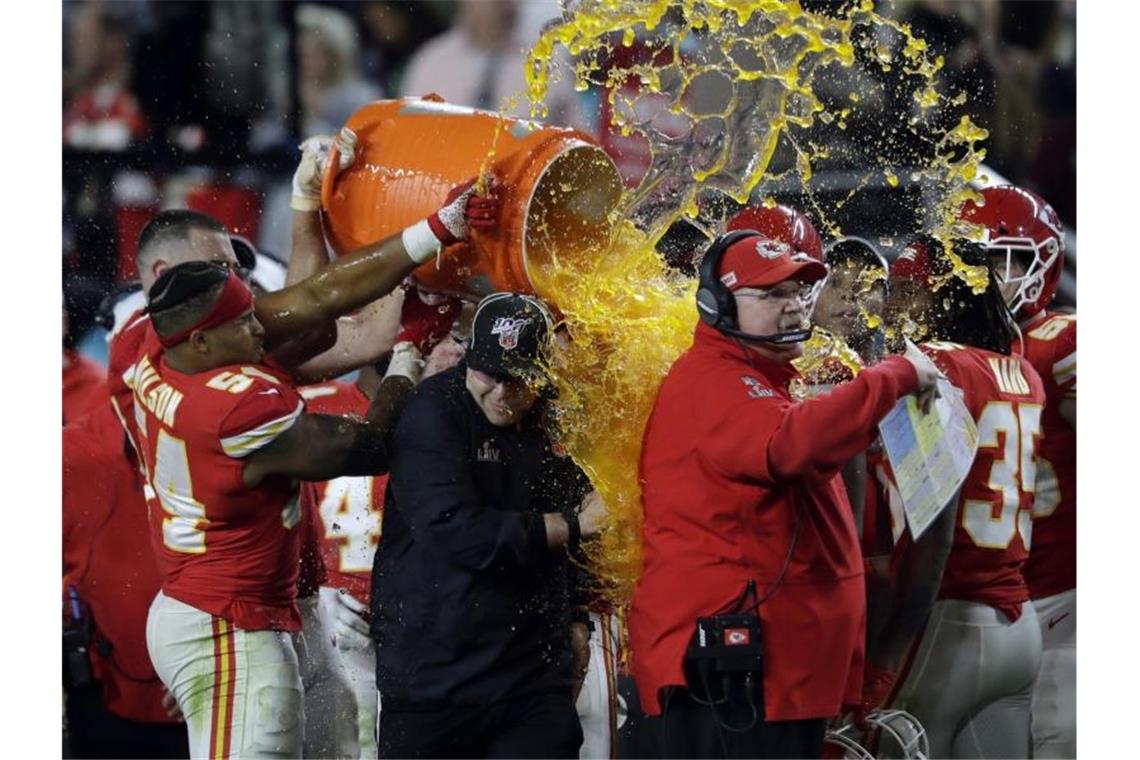 Die Spieler der Kansas City Chiefs gießen den klebrigen Inhalt einer Kühlbox über ihren Trainer Andy Reid. Foto: John Bazemore/AP/dpa