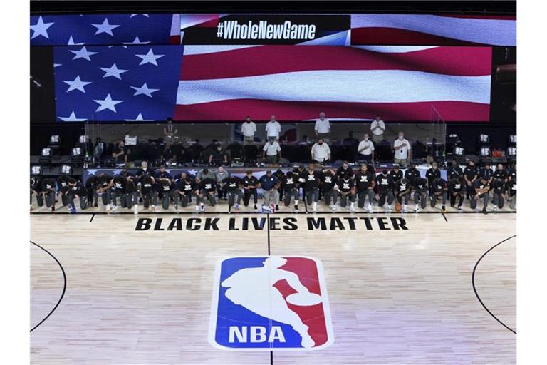 Die Spieler der New Orleans Pelicans und Utah Jazz knien bei der Nationalhymne gemeinsam vor einem „Black Lives Matter“-Schriftzug. Foto: Ashley Landis/Pool AP/dpa