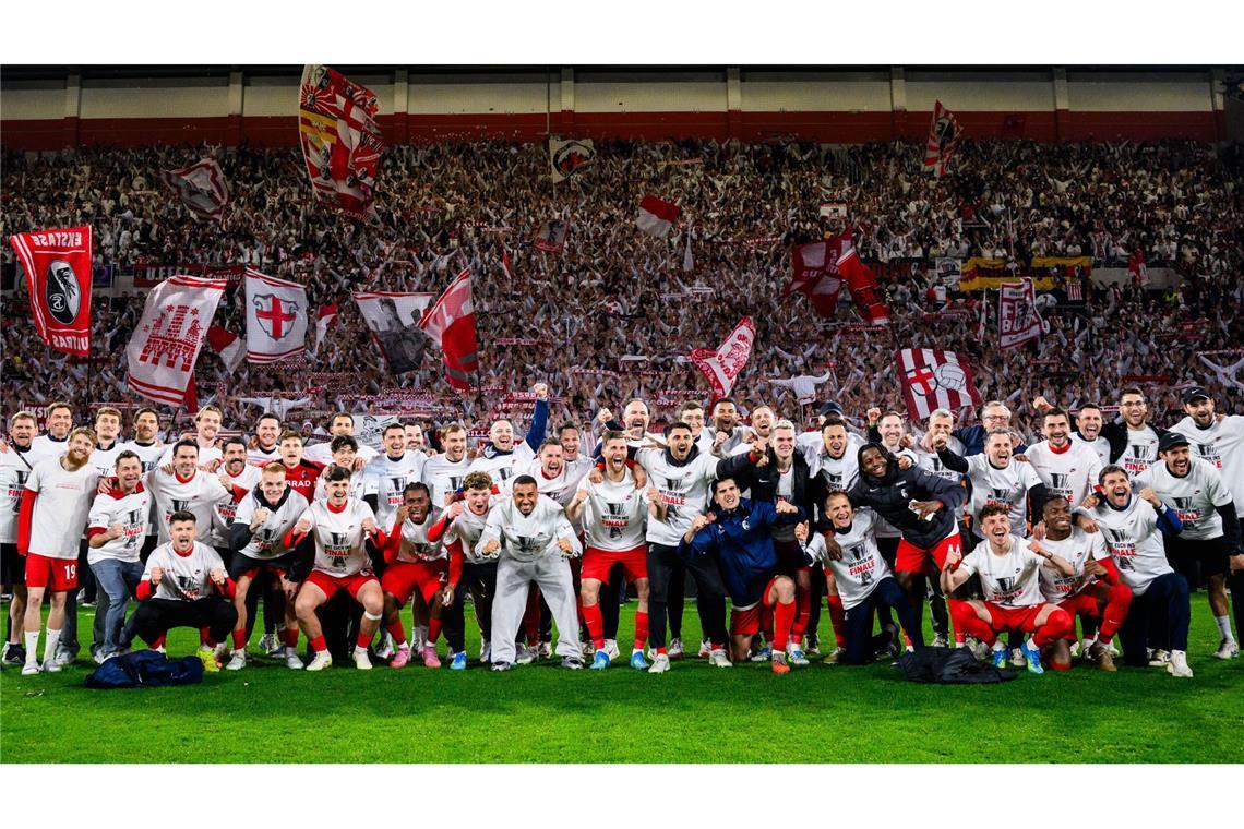 Die Spieler des SC Freiburg jubeln nach dem Einzug ins Europa League Finale bei einem Gruppenbild mit den Fans.