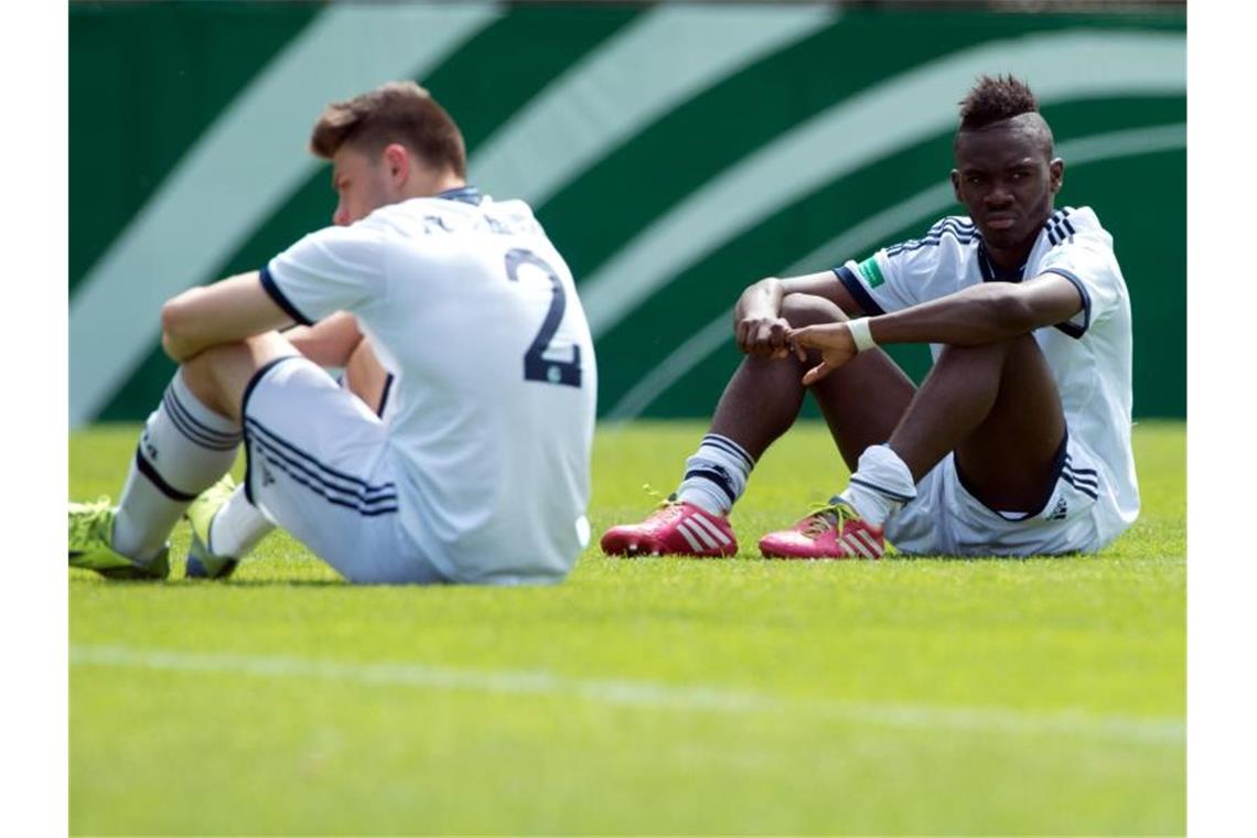 Die Spieler Maurice Multhaupt (l) und Joseph Boyamba (r) sitzen auf dem Spielfeld. Foto: picture alliance / dpa/archiv