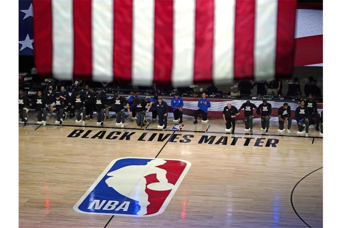 Die Spieler von den Milwaukee Bucks und den Orlando Magic knien vor dem Spiel nieder. Foto: Ashley Landis/AP/dpa