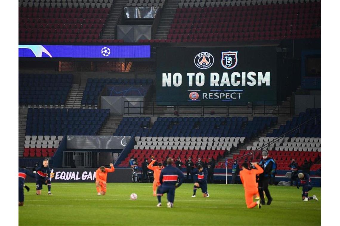 Die Spieler von Paris Saint-Germain und Istanbul Basaksehir sowie die Schiedsrichter knien vor dem Champiopns-League-Spiel als Zeichen der Solidarität mit der Anitrassimus-Bewegung nieder. Foto: Franck Fife/AFP/dpa