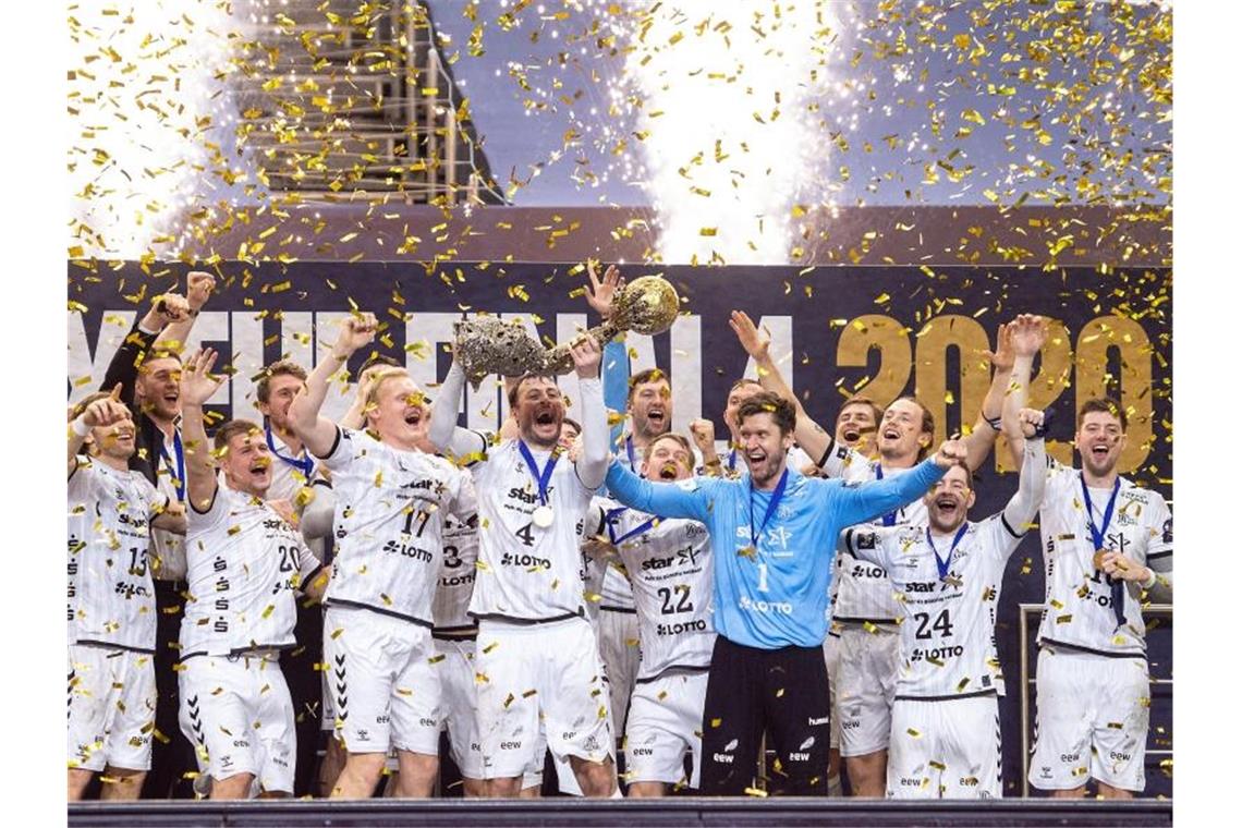 Die Spieler von THW Kiel jubeln im Konfettiregen mit dem Pokal. Foto: Marius Becker/dpa