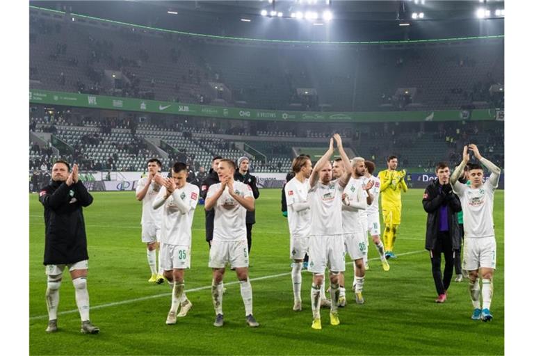 Die Spieler von Werder Bremen feiern den Sieg in Wolfsburg vor ihrer Fankurve. Foto: Swen Pförtner/dpa