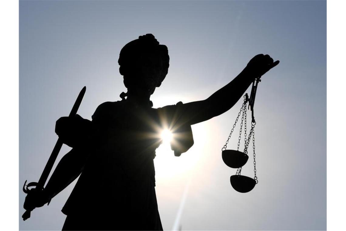 Die Statue der Justitia steht im Gegenlicht der Sonne. Foto: Arne Dedert/dpa/Symbolbild