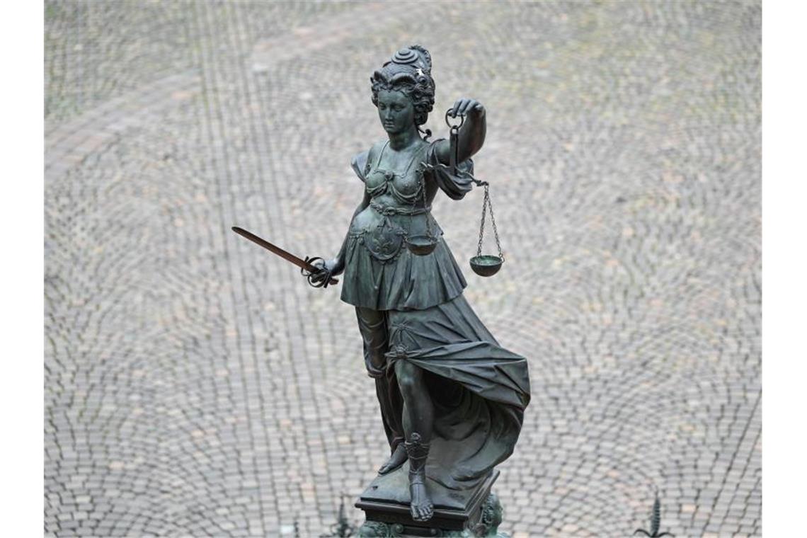 Die Statue der Justitia steht mit einer Waage und einem Schwert auf einem Platz. Foto: Arne Dedert/dpa/Archivbild