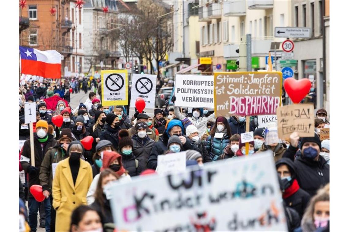 Die Teilnehmer einer Demonstration gegen die Corona-Maßnahmen stehen vor dem Start und tragen dabei Schilder. Foto: Philipp von Ditfurth/dpa