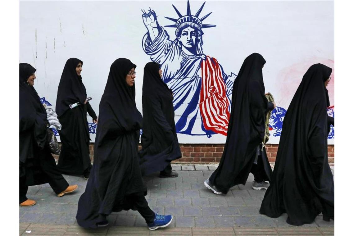 Die Teilnehmerinnen einer Trauerzeremonie für den getöteten General Soleimani gehen auf ihrem Heimweg an der satirischen Zeichnung einer verstümmelten Freiheitsstatue vorbei. Foto: Vahid Salemi/AP/dpa