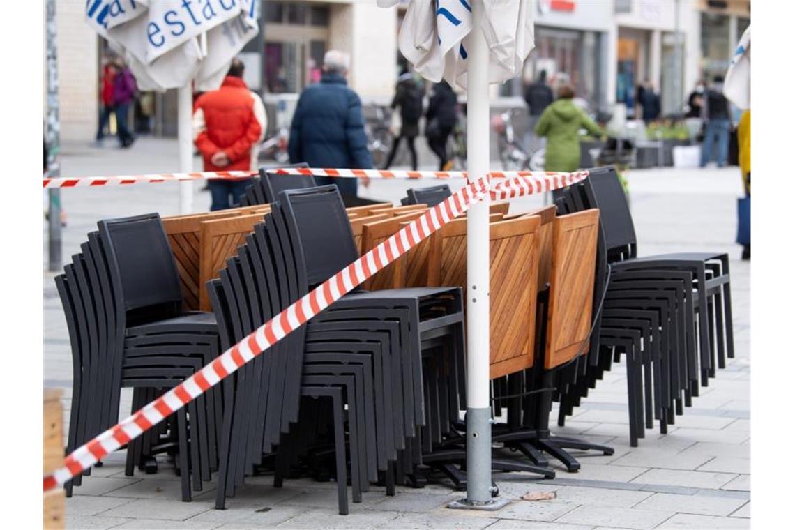 Merkel: Deutschland muss „Corona-Notbremse“ ziehen Die Tische und Stühle eines Cafes sind mit Flatterband abgesperrt. Foto: Sven Hoppe/dpa