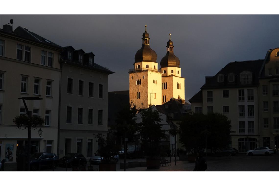 Die Türme der Johanniskirche in Plauen werden von der untergehenden Sonne beschienen.